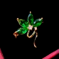 Macro view of gold flower brooch with marquise-cut emerald green and clear zircon stones - Green Petal Floral Style (B752)