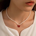 Detail of elegant pearl necklace with red butterfly pendant on a female neck - Red Butterfly Pendant Pearl Necklace