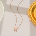 Close-up of rose gold titanium necklace with sparkling diamond-set H pendant on beige background - Iced Out H Style (8806) / Rose Gold