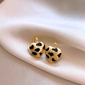 Détail de boucles d'oreilles cœur dorées et noires sur un fond de tissu en soie champagne - 55#Anneau-Or-Cœur