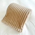 Coperta di flanella beige spessa con motivo a strisce larghe, piegata su letto bianco - Costine Cammello Chiaro