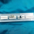 Acrylic jewelry display with a diamond heart ring and a black gemstone ring - 4 Slots Brushed Base White Velvet 15*3.5CM