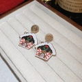 Detail of gingerbread house Christmas stud earrings resting in a beige velvet jewelry box - Christmas Gingerbread House Style
