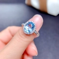 Detail of silver ring featuring oval blue topaz stone with a halo of small diamonds - Adjustable Open / Sea Blue Stone (Silver Tone)