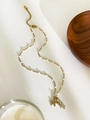 Close-up of a gold starfish necklace with white beads and rhinestone accents on cream background - Gold Starfish Style
