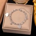 Detail of silver double-layer bracelet with heart charms on pink jewelry display - Double Peach Heart Silver