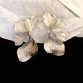 Close-up of large silver 3D floral earrings with intricate metallic petal textures - Silver