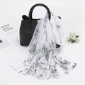 Chiffon floral scarf with grey ink print draped over a black textured leather handbag - Grey White (Artistic Floral)