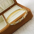 Narrow gold stainless steel bangle with diamond accents and T-shape design on wooden box - Gold