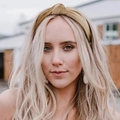 Close-up of a yellow velvet knotted headband for women shown on a model outdoors - Camel