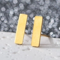 Macro shot of minimalist gold rectangular bar earrings on textured white stone surface - Rectangle / Gold