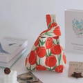 Detail of knitted tote bag featuring red tulip patterns on a cream fabric surface - Tulip Orange Red