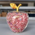 Close-up of a decorative glass apple with pink crystals and a golden leaf accent - Rainbow