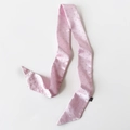 Detailansicht eines rosa Satin-Schals mit silbernen Nieten und glatter Textur - Rosa