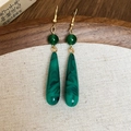 Dettaglio di orecchini retrò con pendenti in agata verde su un vassoio di legno vintage - Verde
