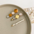 Detailed view of pearl and gold hair clips arranged on a beige ceramic jewelry plate - Style 3 (3-Piece Set/Geometric Yellow-Pink-Silver)