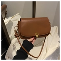 Close-up of brown leather shoulder bag featuring a gold round buckle and knot strap detail - Brown
