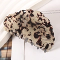 Detail view of a tortoiseshell acetate hair claw clip with a shell shape on a white surface - 8.2cm / Beige