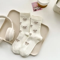 Beige cotton ribbed crew socks with brown embroidered bows in a lifestyle setting - One Size / Off-White (HT39)