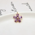 Detailed macro of a purple zircon five-petal flower pendant with gold plated settings - Violet