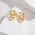 18K gold plated stainless steel monstera leaf stud earrings on a white textured stone base - Gold Hollow Leaf Drop Earrings (E941-02)