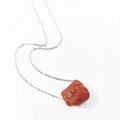 Close-up of raw reddish-brown natural crystal pendant on a fine silver-tone chain - Red Agate