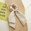 Detalle de un coletero beige con flores y lazo sobre una bandeja de madera decorativa - Amarillo Limón Doble Capa