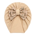 Detailed knit texture of beige baby turban featuring a large floral daisy bow decoration - Light Coffee