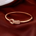 Close-up of rose gold horseshoe buckle bracelet with zircons on dark red silk - Gold