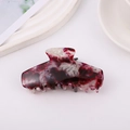 Dettaglio di una grande pinza per capelli in acetato marmorizzato lucido ed elegante - Rosso Scuro