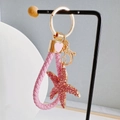 Detailed close-up of a pink rhinestone starfish keychain with woven leather rope strap - Starfish + Heart Strap / Light Pink