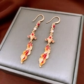 Detalle de pendientes de pez koi con esmalte rojo y perlas pequeñas sobre un joyero - Gancho de oreja - Dorado - Koi