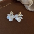 Detalle de pendientes de flores blancas con toques dorados y circón sobre fondo marrón - 3# Pin de Plata - Oro - Concha Blanca
