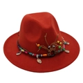 Close-up of deep red fedora hat with ethnic beads and seashell decorative band - Rust red
