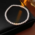 Détail macro d'un élégant bracelet en perles roses sur cuir noir et lumière chaude - Style de Perles Roses 4mm