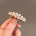 Dettaglio dell'elegante fermaglio dorato per capelli con perle bianche di varie dimensioni - Clip a molla con perle / Oro