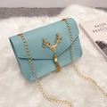 Light blue crossbody bag with gold deer head emblem and chain strap on white fur - Blue
