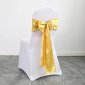 Golden satin chair sash tied in a large bow over a white wedding chair cover for events - Gold