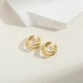 Dettaglio dell'orecchino ear cuff dorato multistrato su sfondo in pietra testurizzata - Oro multistrato