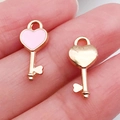 Pink heart-shaped key charms for DIY jewelry making on a fingertip close-up - Pink Heart Key (10989)