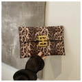 Detail of leopard print clutch with a geometric gold metal buckle held by a model - Brown