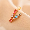 Macro shot of letter A pendant in gold with colorful inlaid zircon stones - Letter V