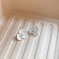 Detailed macro view of elegant white flower stud earrings with a pearl center on textured tray - White