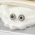 Macro shot of silver evil eye stud earrings on a white relief base and cream silk - Silver Grey Glitter Eye