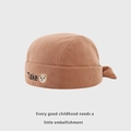 Detail of brown corduroy baby beanie with embroidered bear and Take lettering texture - 48cm / Caramel color