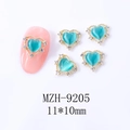 Détail macro du bijou d'ongle cœur œil de chat avec dentelle dorée en 11x10mm - Cœur bleu clair avec cadre doré (9205)