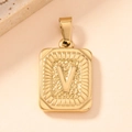 Detailed macro of gold square pendant with embossed V and vintage sunburst texture - Letter V