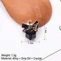 Makro-Detail einer schwarzen Emaille-Schleife mit Kristall-Anhänger, Maße 1,4x1,2 cm - Schwarz