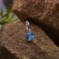 Macro detail of a 925 sterling silver pendant with a blue gemstone on a natural rock - Natural Topaz Round Pendant Silver
