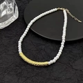 French style pearl necklace with gold textured metal bar on a black decorative plate - Gold